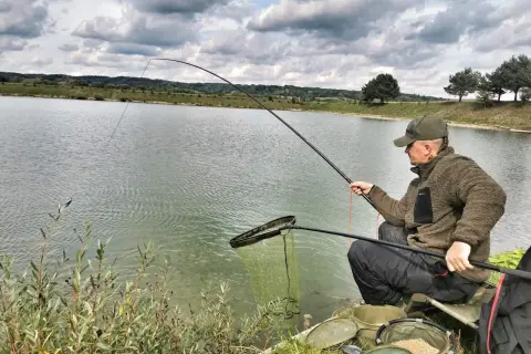 Wędkarz łowi na tyczkę z amortyzatorem. Dobór grubości gumy do wielkości ryb jest kluczowy dla sukcesu.