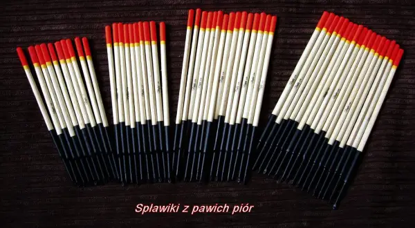 Spławik z pióra pawia – dlaczego wciąż jest niezastąpiony? Kilka rzędów tradycyjnych spławików wędkarskich, wykonanych z jasnego materiału z czarnym ogonkiem i czerwono-żółtą końcówką.