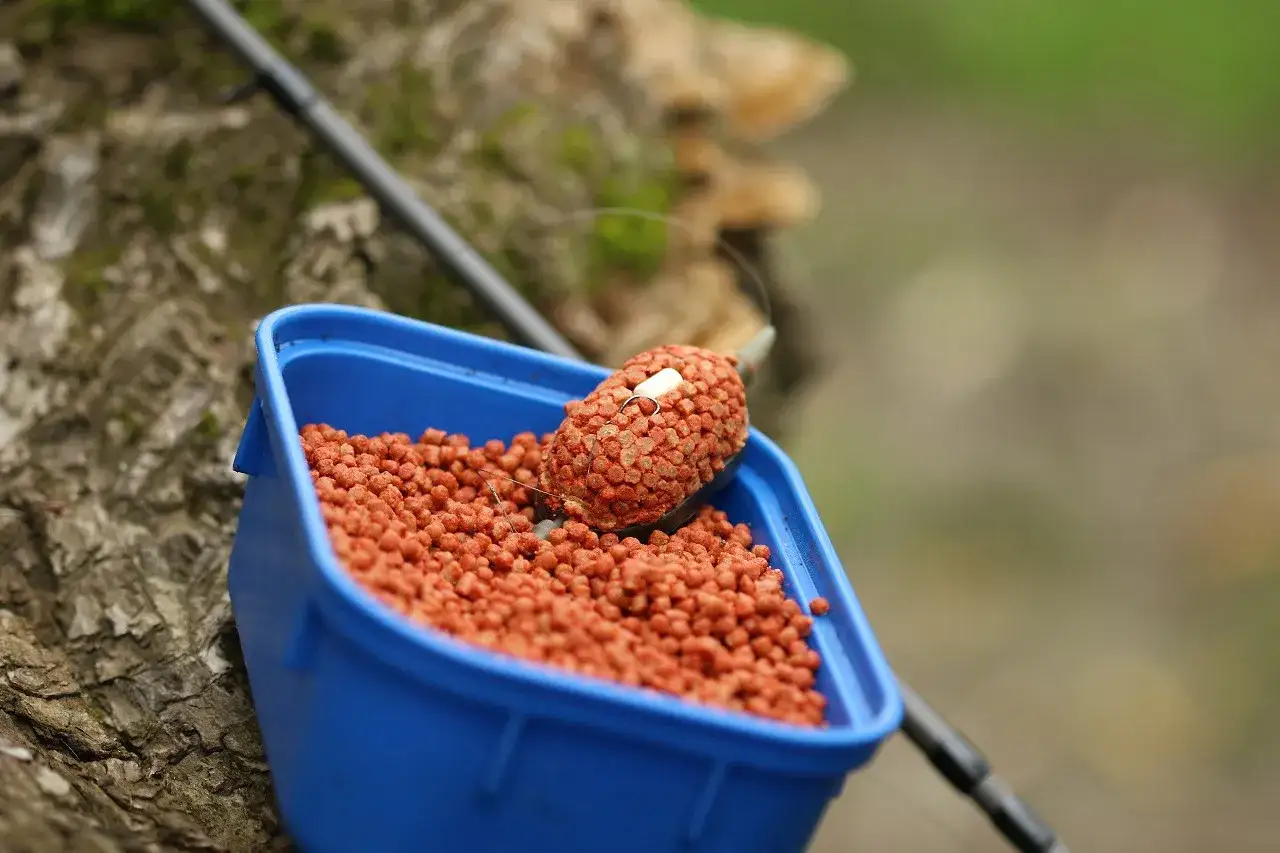 Idealne nawilżenie pelletu do podajnika method feeder to klucz do sukcesu. Widać tu gotowy do użycia pellet w niebieskim pojemniku.