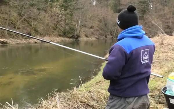 Łowienie z powierzchni na twardy chleb. Jak nie płoszyć kleni i jazi? Wędkarz z wędką nad rzeką.